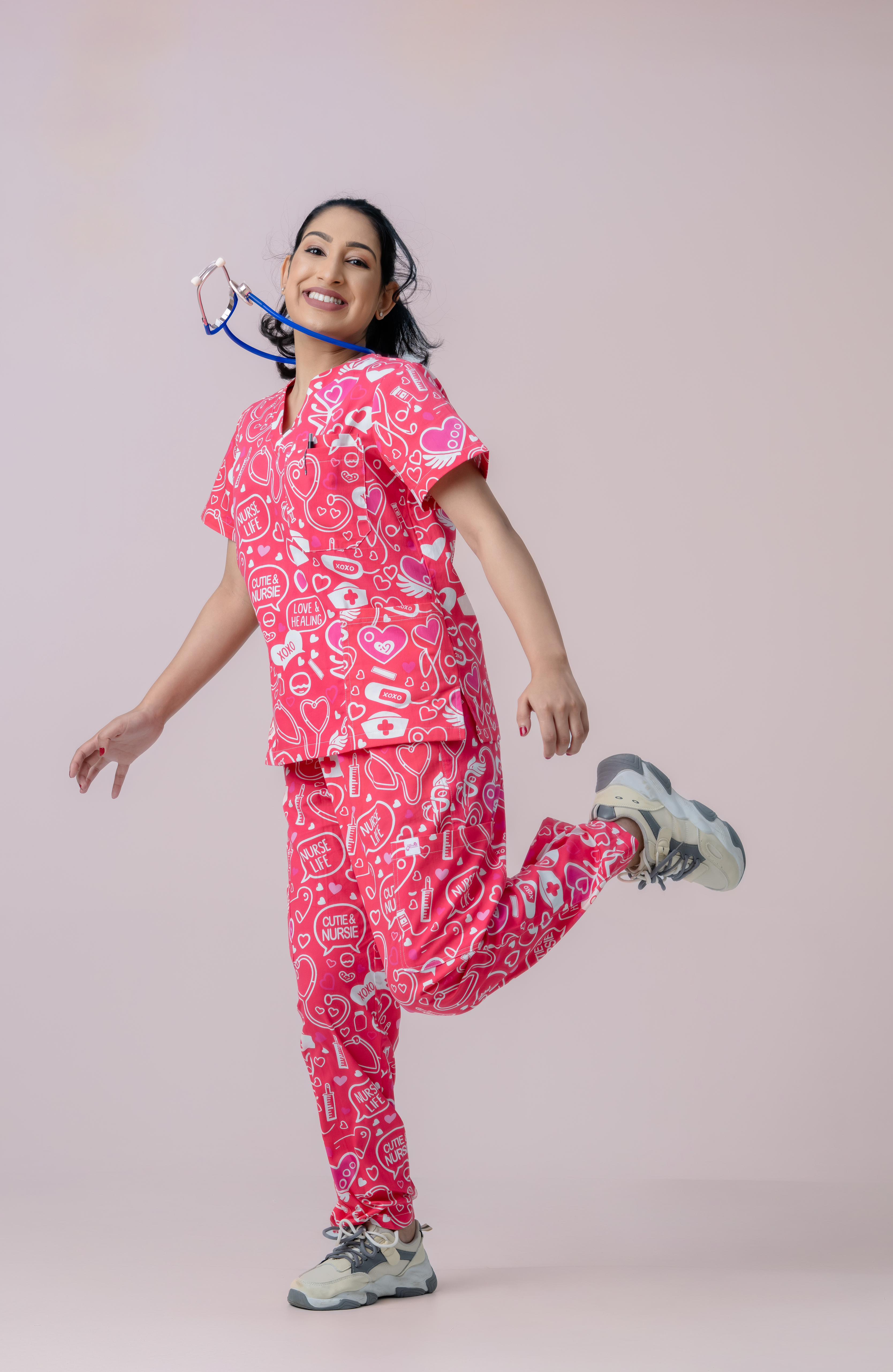 Female healthcare professional wearing pink heart print scrub uniform posing playfully