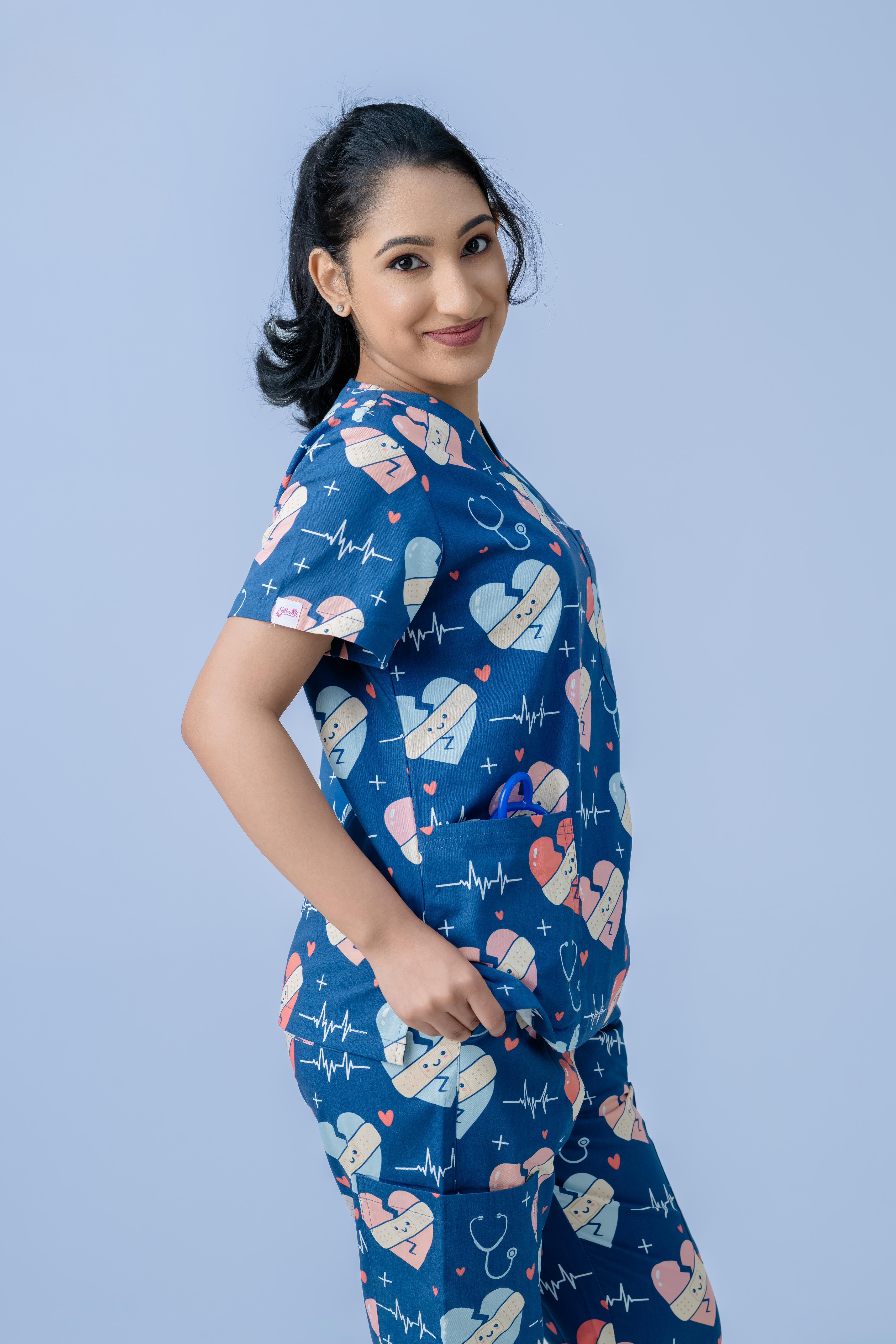 Female healthcare professional wearing navy blue heart print scrub uniform